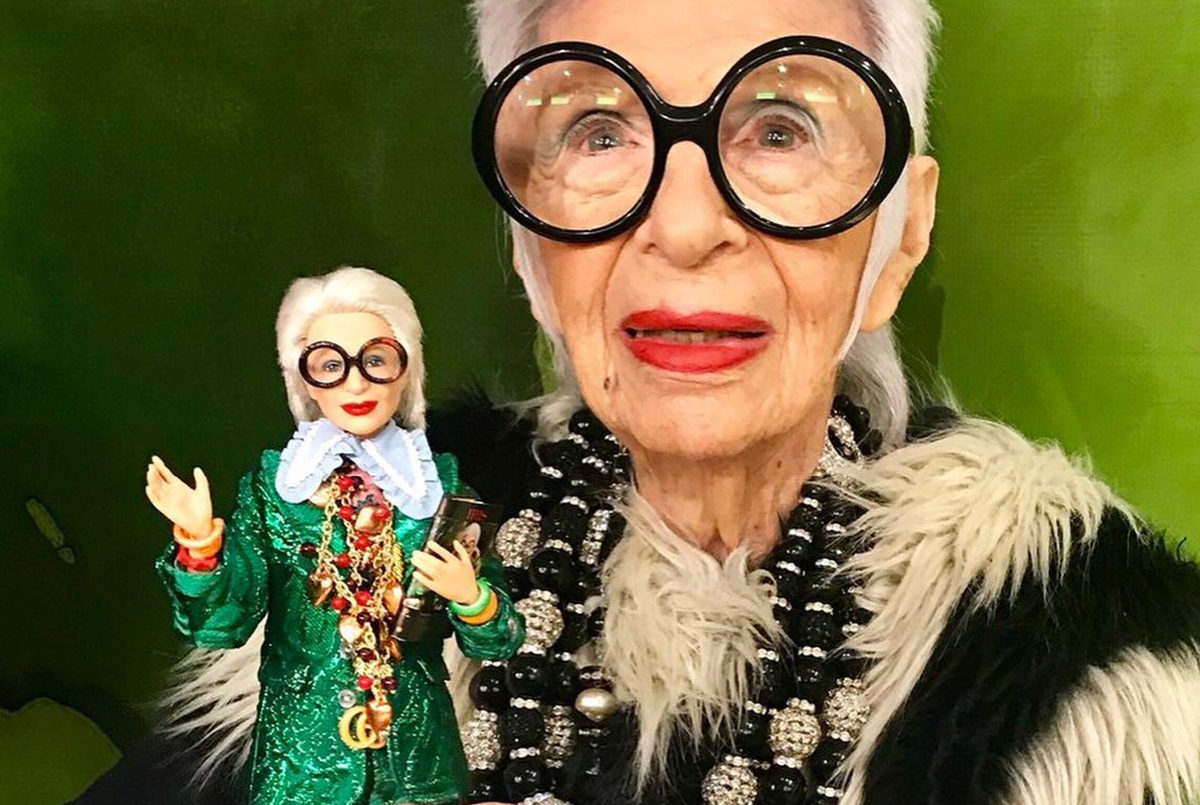 Iris Apfel s veľkými okuliarmi vedľa bábiky Barbie, ktorá ju zobrazuje